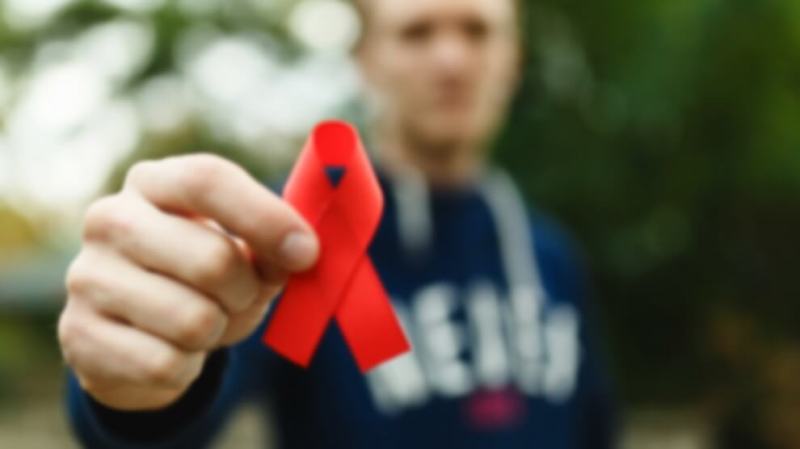 bigstock-red-aids-ribbon-in-hand-on-gre-351048632-990x556 (1)